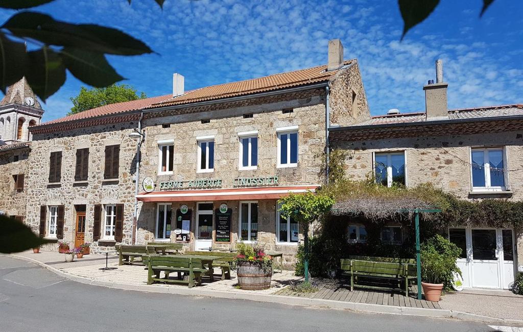 - un bâtiment en pierre avec des tables de pique-nique devant dans l'établissement Ferme Auberge Linossier, à Burdignes