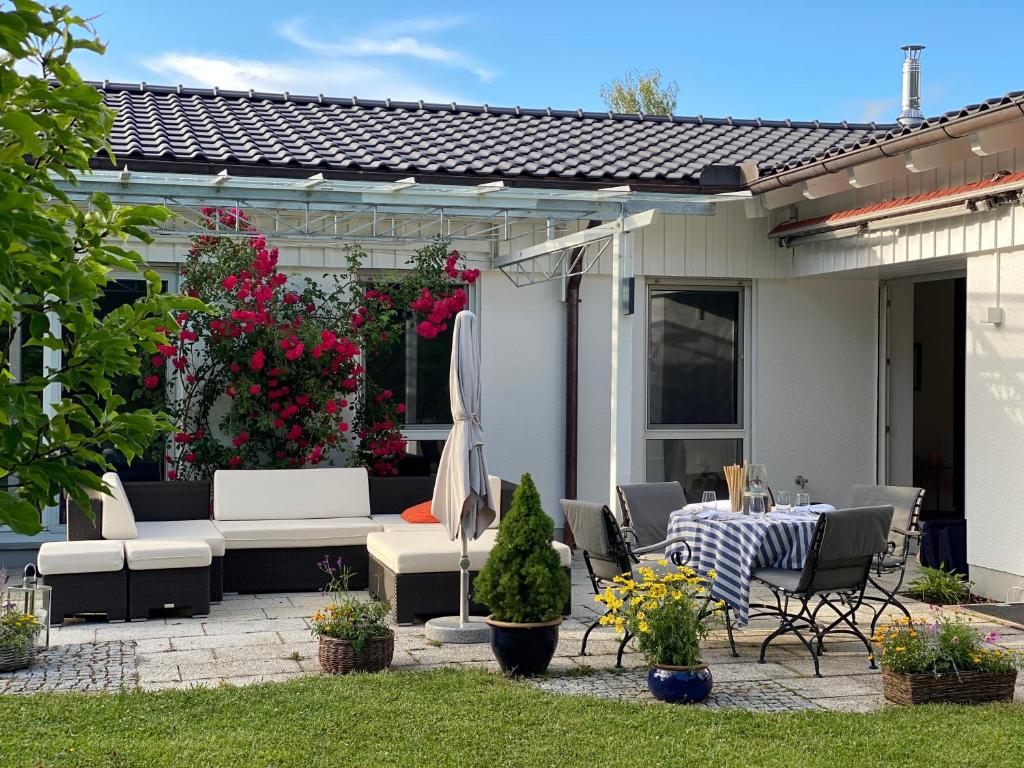 eine Terrasse mit einem Tisch, Stühlen und Blumen in der Unterkunft Villa Starnberger See in Pöcking