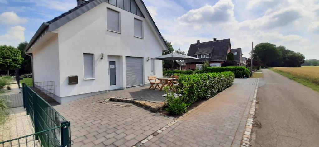 a white house with a table and an umbrella at Am Habichtsweg in Lengerich