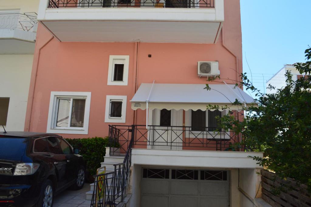 una casa rosa con un coche aparcado delante de ella en Anastasias Apartment center City by Dimitropoulos en Aigio