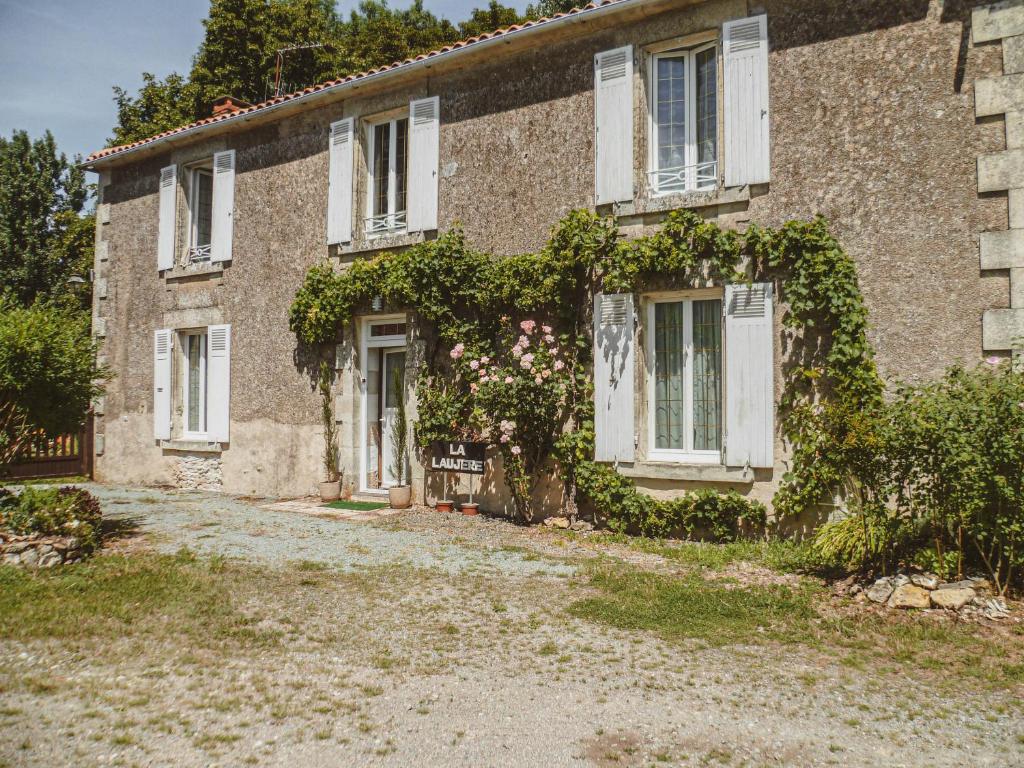 una vecchia casa di mattoni con finestre bianche ed edera di LA LAUJÈRE Chambres d'hôtes ROMANCE a La Caillère