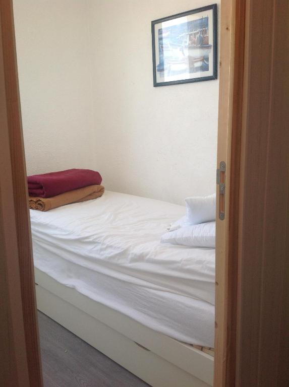 - un lit avec des draps blancs et une photo sur le mur dans l'établissement La Triere, à Saint-Hilaire-de-Riez