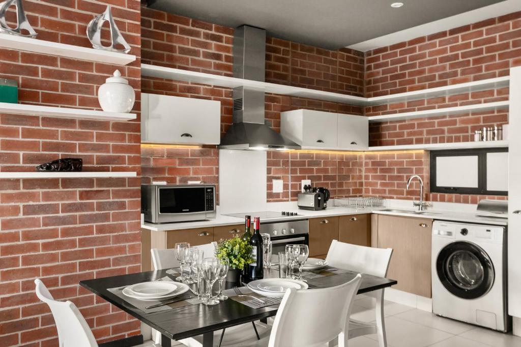 a kitchen with a table and a brick wall at Easy Stay - The Vantage Rosebank in Johannesburg