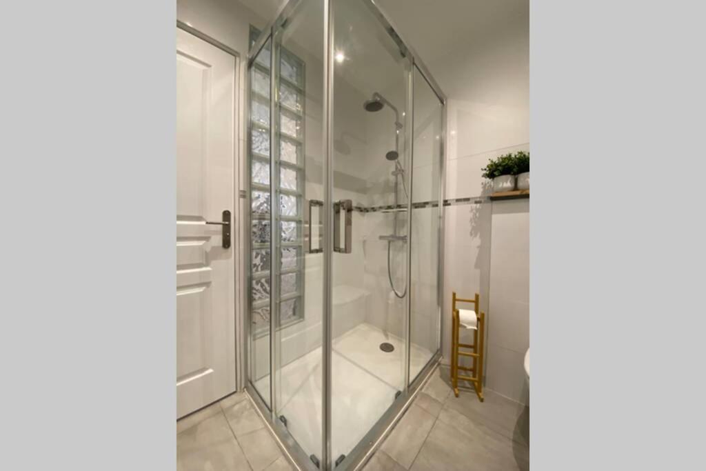 a shower with a glass door in a bathroom at Studio de charme - calme, discret &amp; cosy - 3&#39; RER in Évry-les-Châteaux