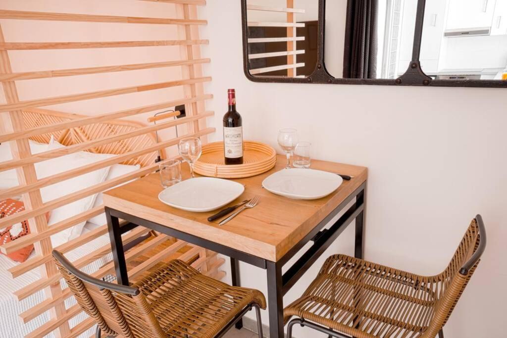 a table with a bottle of wine and two chairs at Studio de charme - calme, discret &amp; cosy - 3&#39; RER in Évry-les-Châteaux