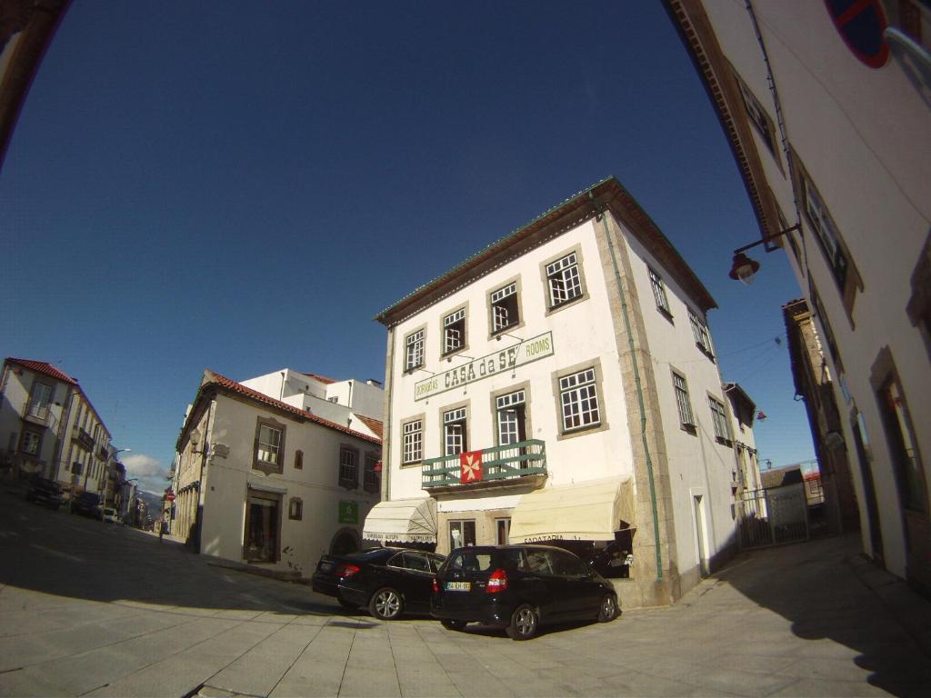Biały budynek z dwoma samochodami zaparkowanymi przed nim w obiekcie Guesthouse da Sé w mieście Guarda