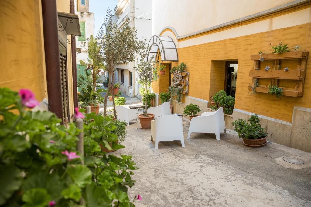 une cour avec des chaises et des plantes blanches et un bâtiment dans l'établissement Hotel Clelia, à Ustica