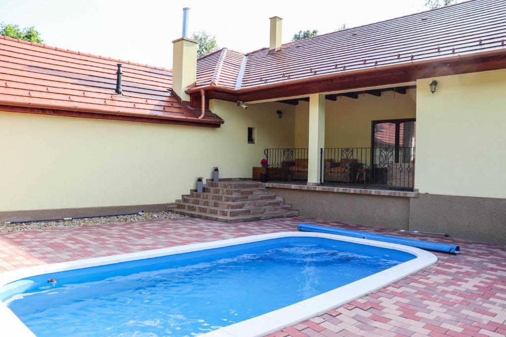 a swimming pool in front of a house at Forest Luxury Apartman in Dorogháza
