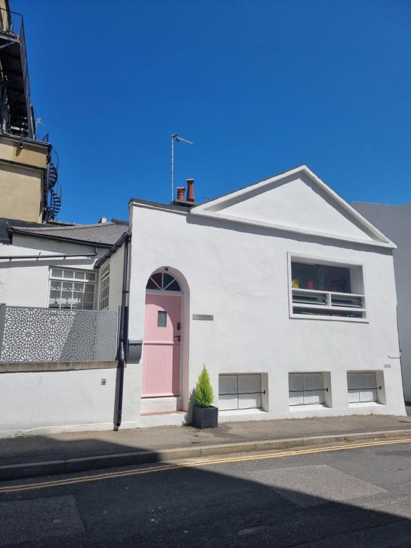 a white building with a pink door on a street at Quirky Seaside Family Cottage walk to the waves! in Brighton & Hove