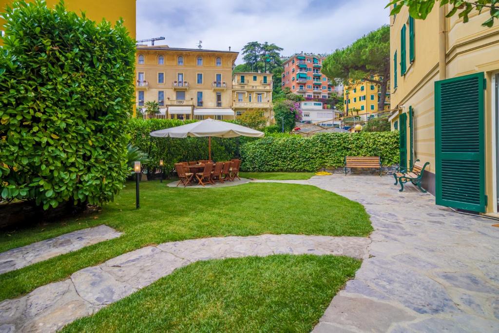 un jardín con sombrilla, bancos y edificios en Casa Claudia, en Rapallo