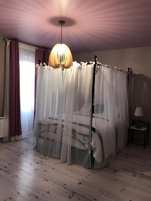 a bedroom with a bed with white curtains and a chandelier at Saint Vincent in Bué