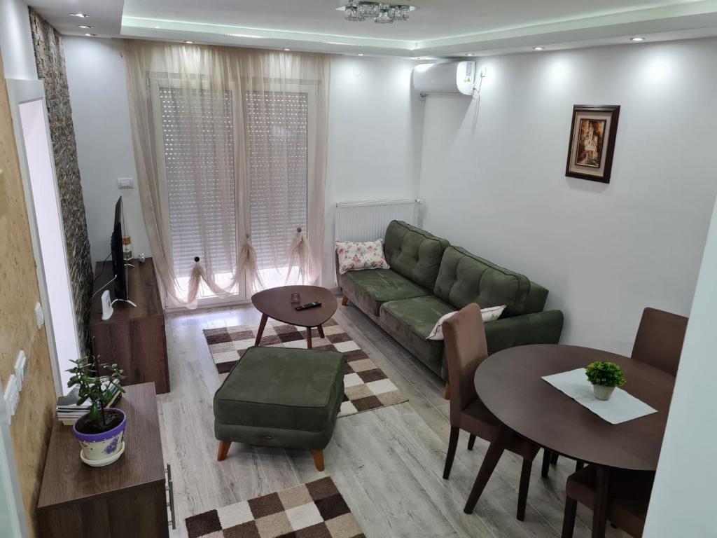 a living room with a green couch and a table at Апартман Андреј in Banja Koviljača