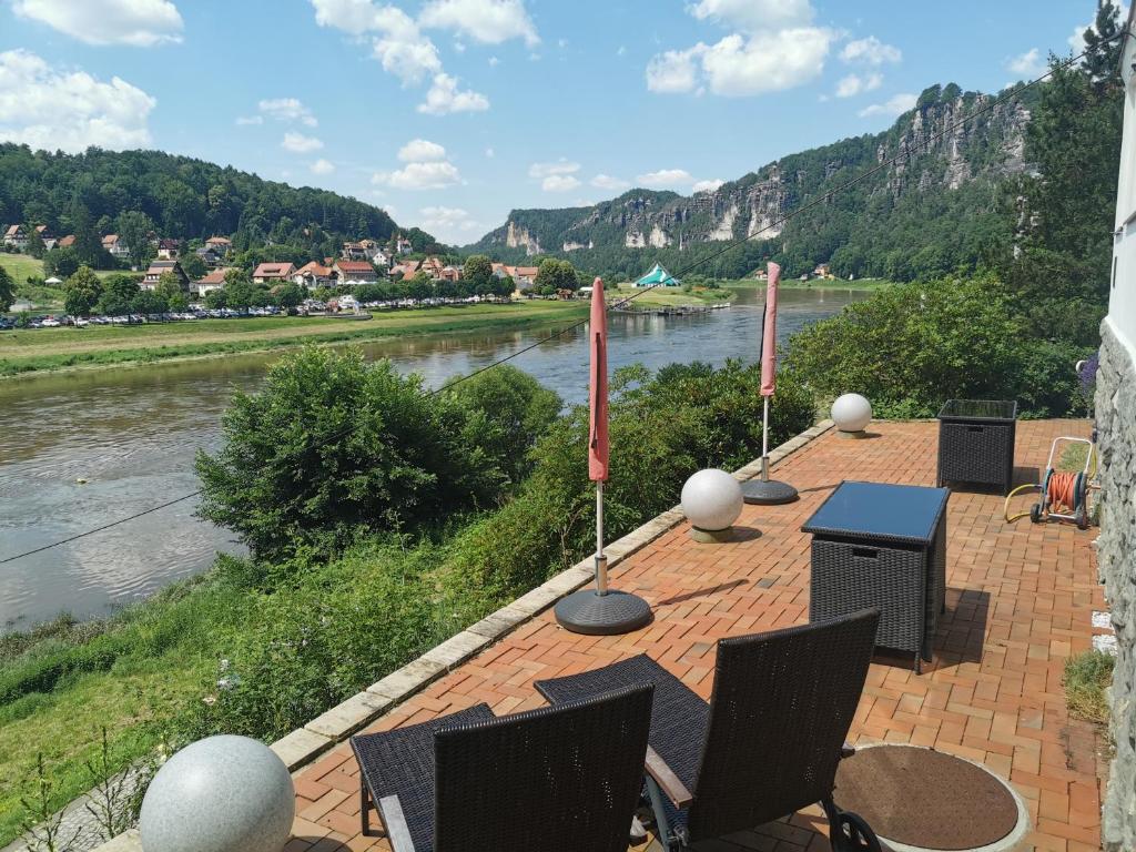 een patio met tafels en stoelen naast een rivier bij Villa Belvedere in Kurort Rathen