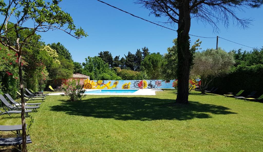 a swimming pool in a park with chairs and a tree at Logis Hotel Restaurant la Ferme in Avignon