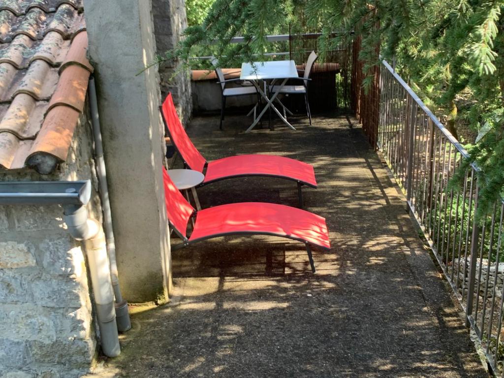 2 chaises rouges et une table sur une terrasse dans l'établissement Chambre d'hôtes climatisée avec terrasse et spa, à Saint Alban Auriolles