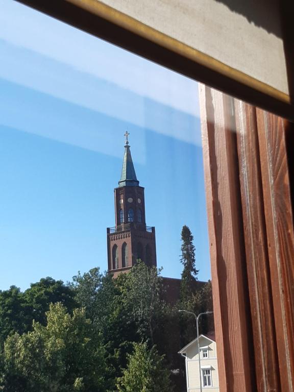 un campanario de la iglesia visto a través de una ventana en Keskustan kaksio parvekkeella, ilmastoitu. en Savonlinna