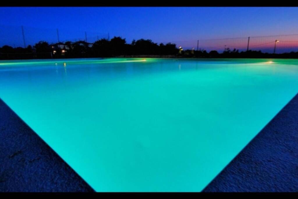ein Pool mit blauen Lichtern am Wasser in der Nacht in der Unterkunft Alavanda Poreč - app s bazenom in Poreč