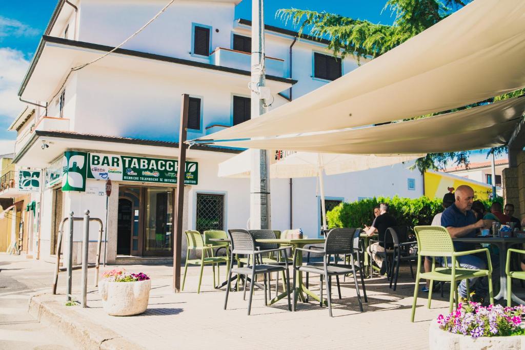 Sale Hotel في بوسادا: مقهى خارجي مع كراسي وطاولات ومظلات