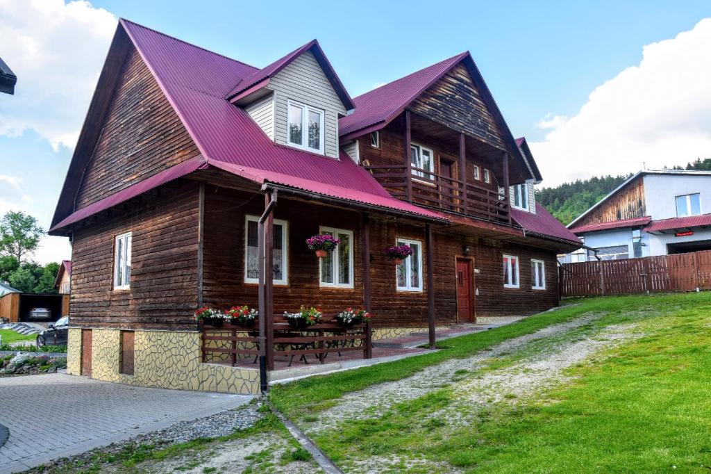 ein großes Holzhaus mit einem lila Dach in der Unterkunft U Janusza in Zadwórze