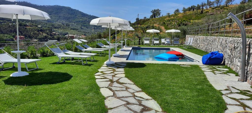 a pool with chairs and umbrellas in a yard at ARIA Design B&B Levanto in Levanto