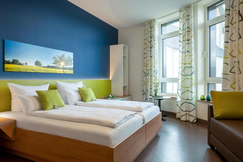 ein Schlafzimmer mit einem großen Bett mit blauer Wand in der Unterkunft Hotel Leib & Seele in Drensteinfurt