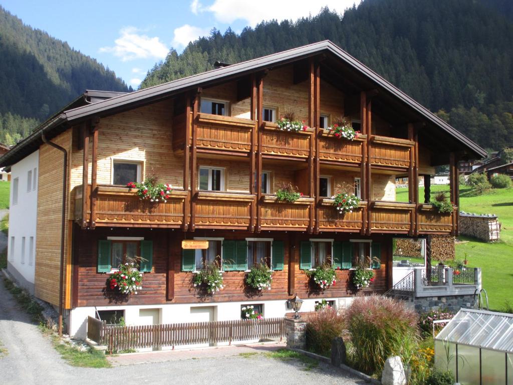 una gran casa de madera con flores en los balcones en Gostanova Appartements, en Gaschurn