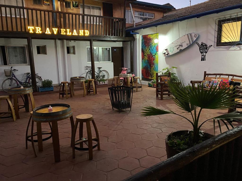 um pátio com mesas e bancos em frente a um restaurante em Hostal Traveland em Pichilemu