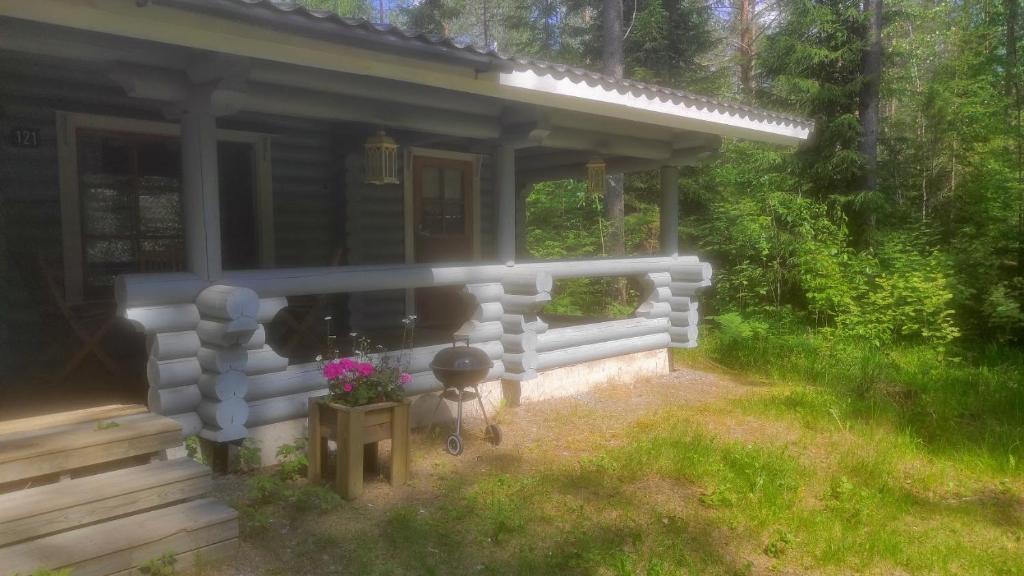 a small house with a porch and flowers in front of it at Holiday Cabin Kerimaa 121 in Savonlinna