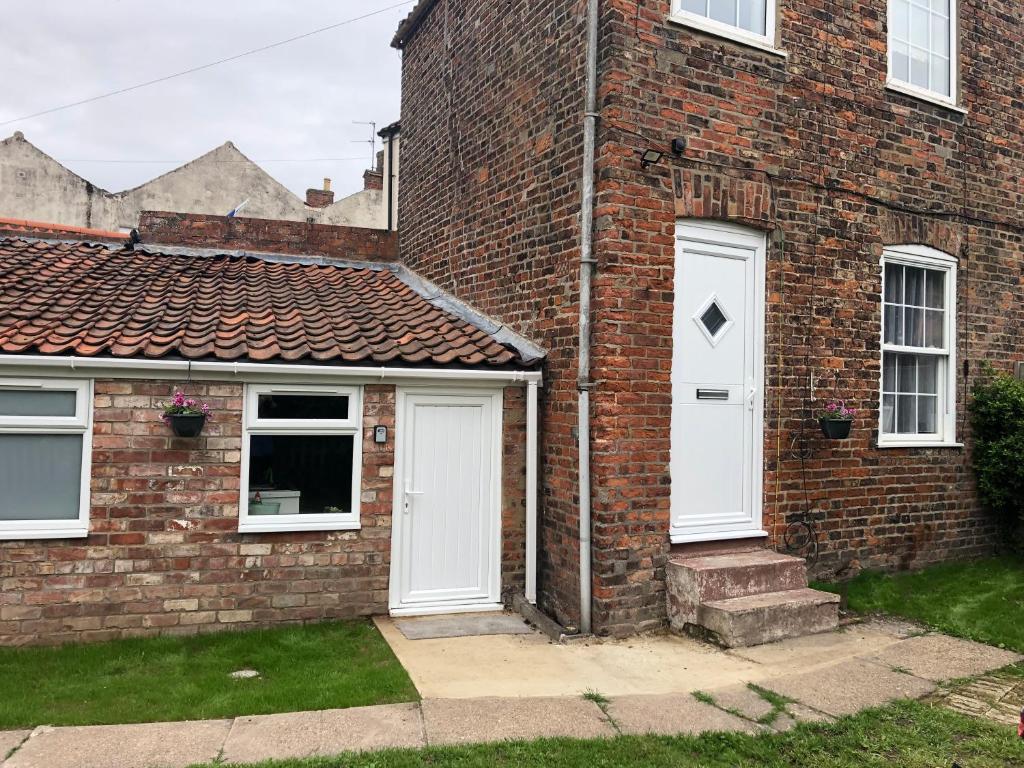 a brick house with two white doors on it at Jasmyne Cottage in Wainfleet All Saints