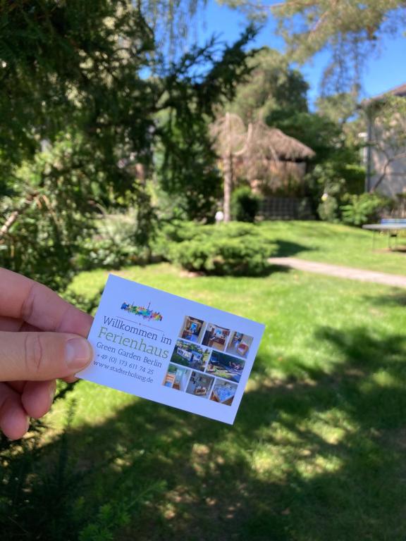 a person holding a card in a yard at Ferienhaus Green Garden Berlin - Welcome to Berlin in Berlin
