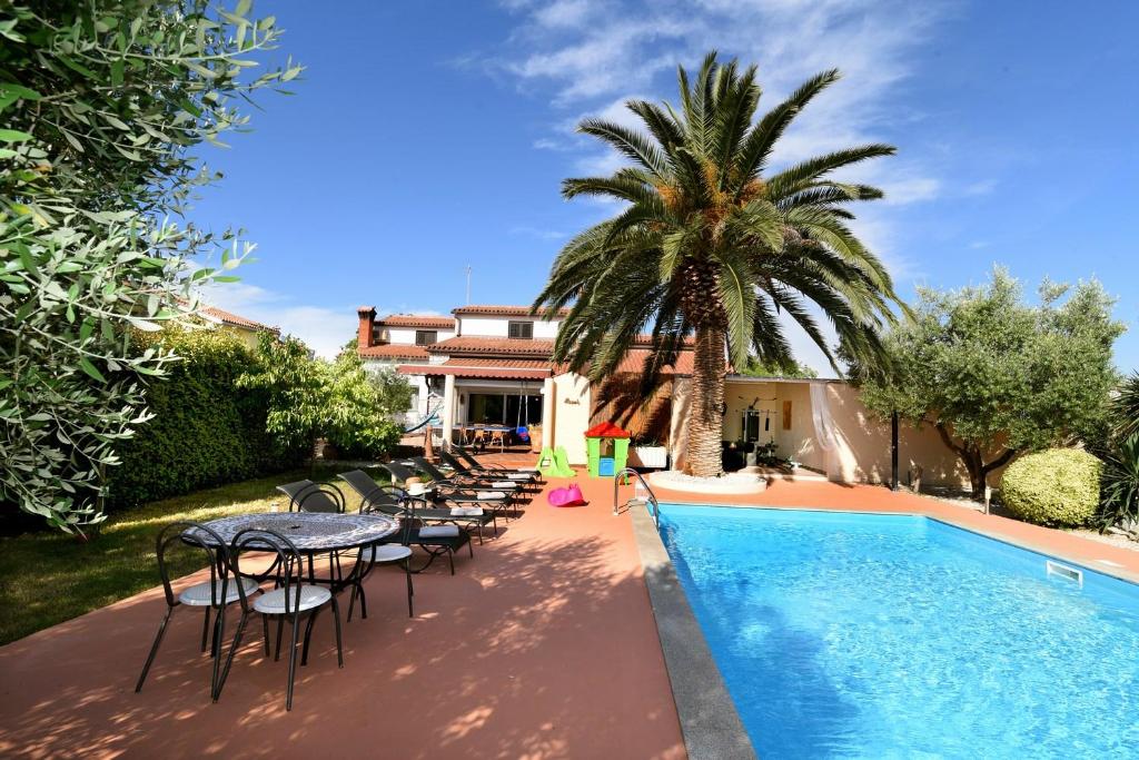 basen ze stołami i krzesłami oraz palmą w obiekcie Holiday Home Villa Margherita w Puli