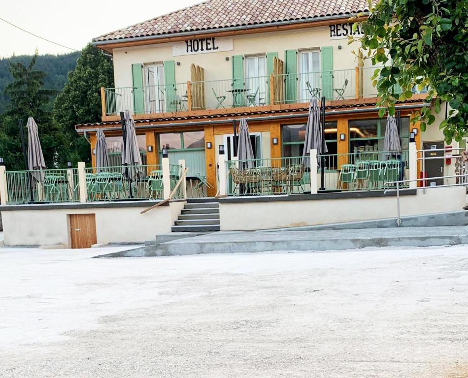 ein Gebäude mit Stühlen und Sonnenschirmen davor in der Unterkunft Hôtel Le Bel Air in Saint-André-les-Alpes