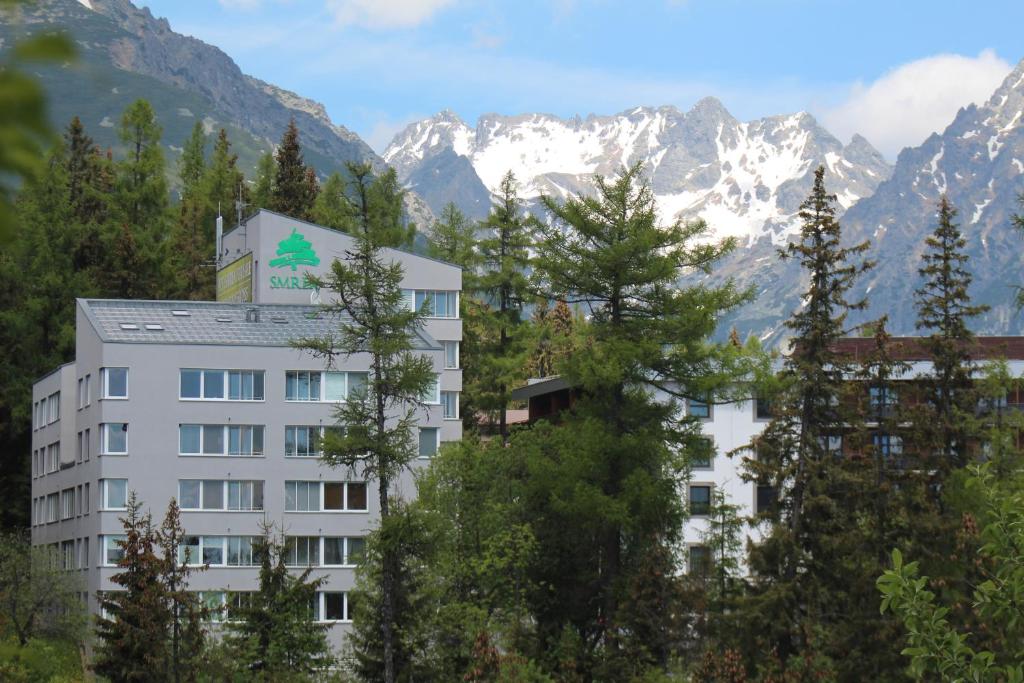 a building with trees in front of a mountain at Strbske Pleso Smrek Penthouse Apartment in Štrbské Pleso
