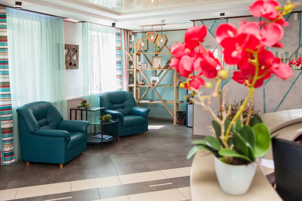 un vestíbulo con 2 sillas azules y flores rojas en Hotel Viktoriya, en Syktyvkar