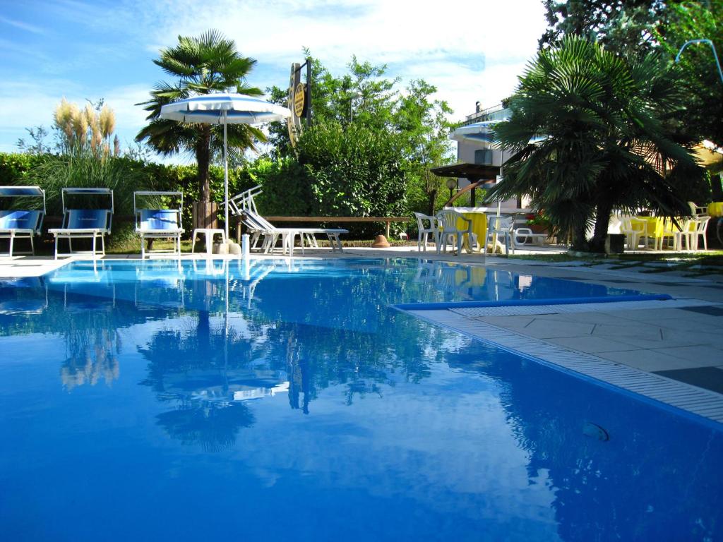 una piscina azul con sillas y sombrilla en Hotel Boomerang, en Tabiano