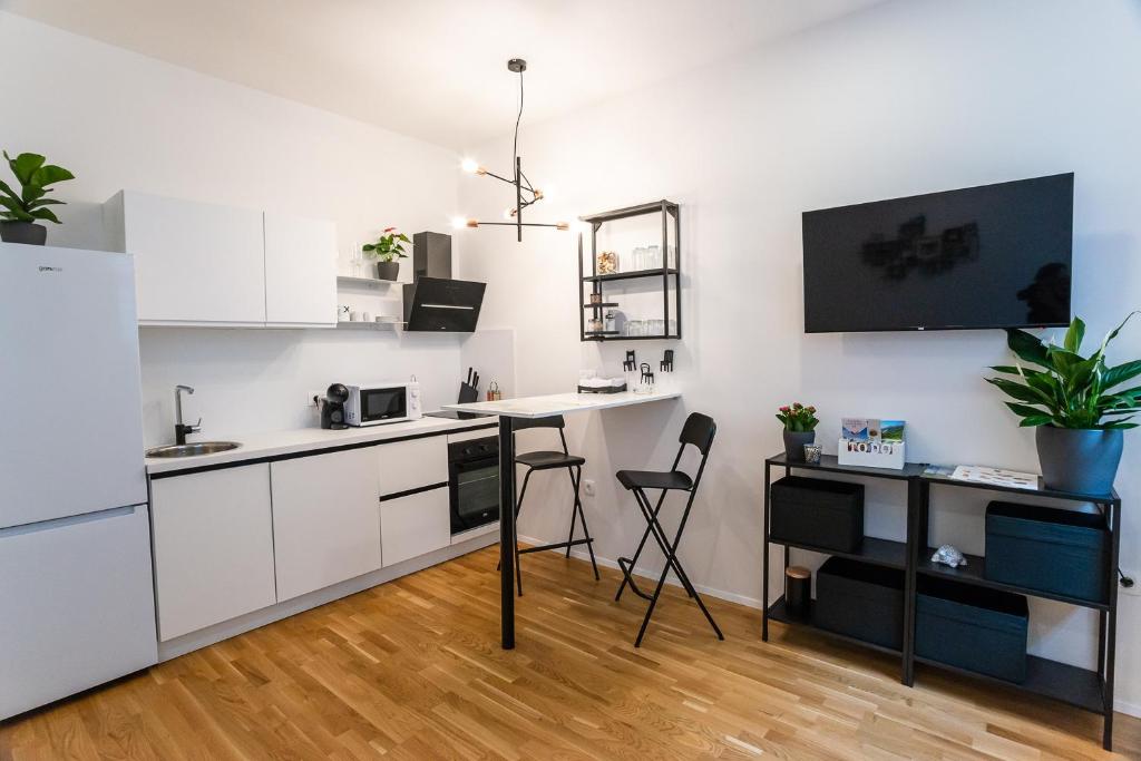 a kitchen with white cabinets and a table and chairs at Loni's Place Apartments in Ljubljana