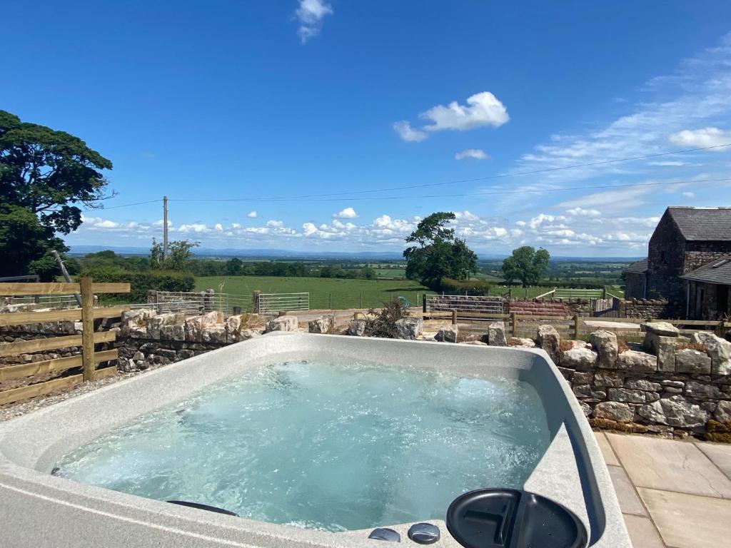 a jacuzzi tub on a patio with a stone wall at Rattlebeck Farm Cottage and Hot Tub PET FRIENDLY in Welton
