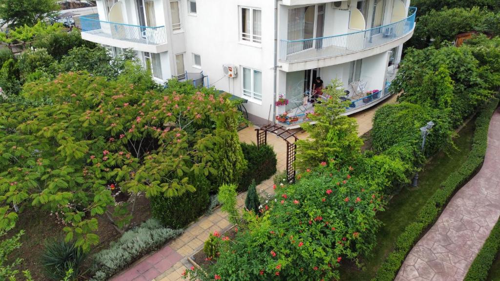 an apartment building with a garden of flowers and trees at Lilia Guest House in Nesebar