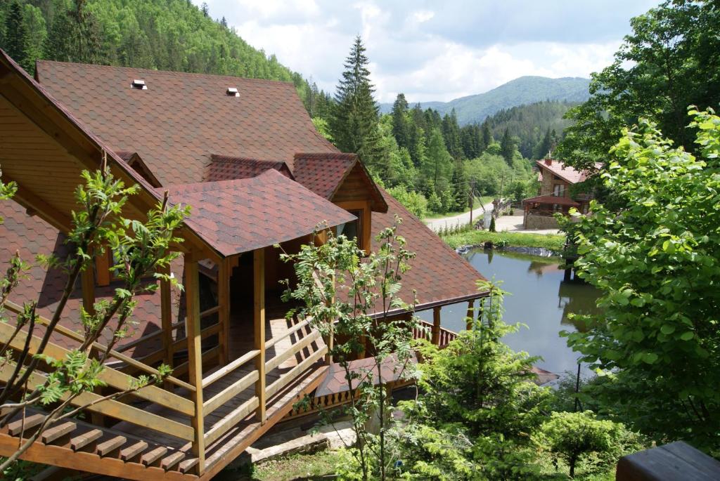 a cabin in the mountains with a lake and trees at Hotel Dykyi Med in Tatariv