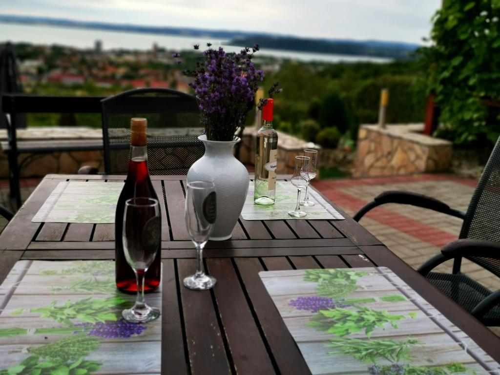 una mesa de madera con copas de vino y un jarrón con flores en Panorama Resort Balatonfüred, en Balatonfüred