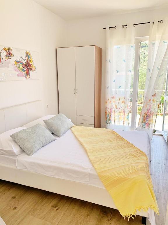 a bedroom with a large white bed and a window at Apartmani Stupin Čeline in Podglavica