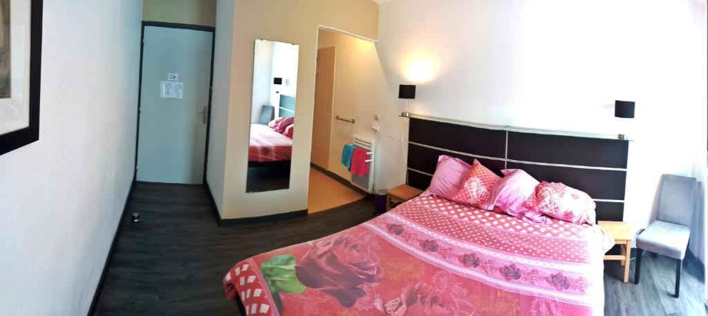 een slaapkamer met een bed met roze lakens en een spiegel bij BonAbri Vacances - Chambres d'hôtes in Chazelles