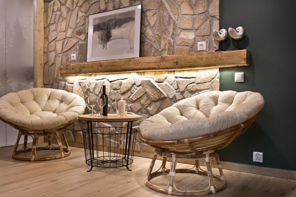 two chairs and a table in front of a stone wall at Apartament Nieoczywisty in Stronie Śląskie