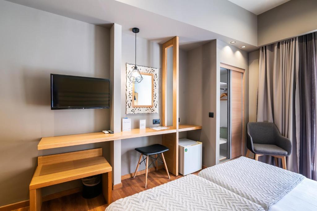 a bedroom with a bed and a desk with a television at Agamemnon Hotel in Nafplio