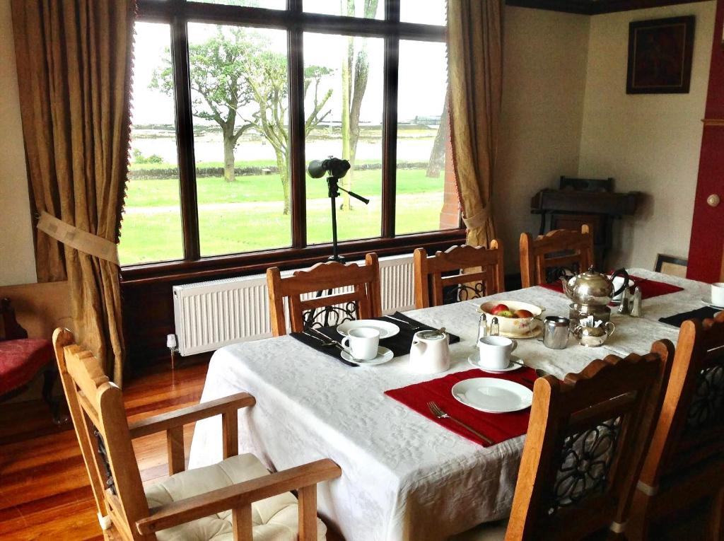 een eetkamer met een tafel met een wit tafelkleed en een tafel bij The Old Vicarage NI B&B in Ballywalter