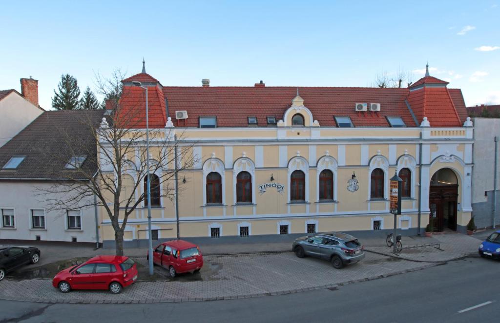 a large building with cars parked in front of it at Tinódi Fogadó in Sárvár