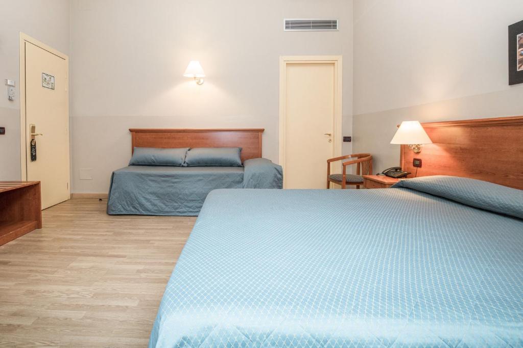 a bedroom with two beds with blue sheets at Hotel Impero in Cremona