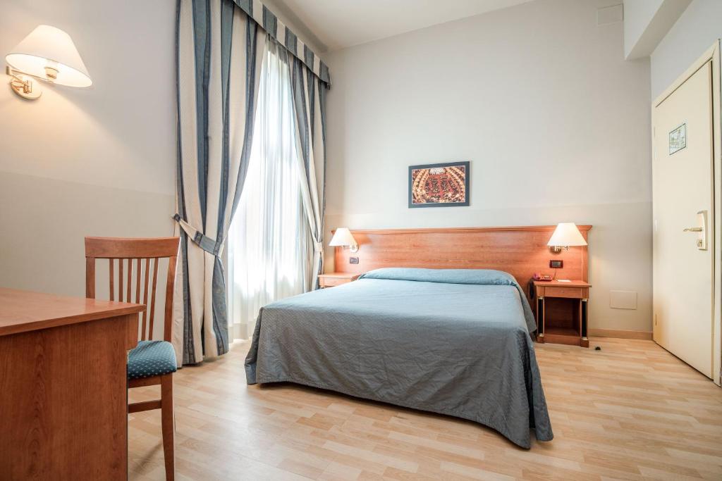 a bedroom with a bed and a desk and a window at Hotel Impero in Cremona