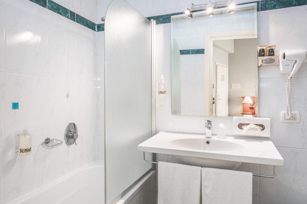 a white bathroom with a sink and a shower at Hotel Impero in Cremona