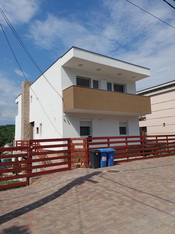 ein weißes Haus mit einem Zaun davor in der Unterkunft Fiesta Apartman in Miskolctapolca